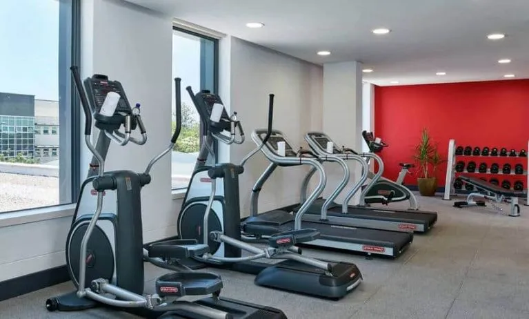 Ellipticals, treadmills, and space for free weights in hotel exercise room.