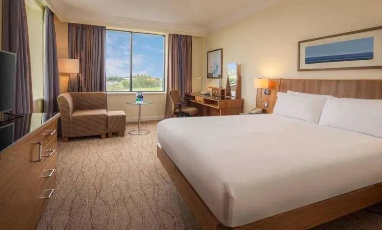 King bedroom with sofa, TV screen and desk at the Hilton Dublin Airport.