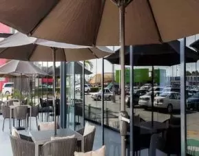 Outdoor terrace with chairs, tables and sun umbrellas at the Hampton Inn by Hilton Cancun Cumbres.