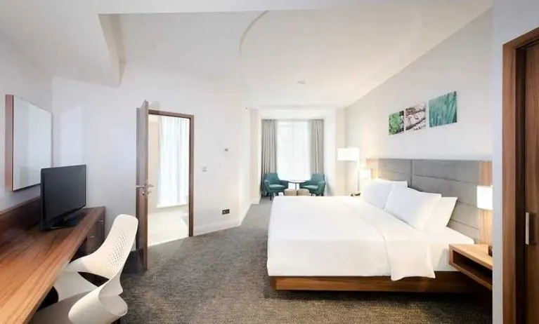 spacious king room with TV, desk, chair, and lots of natural light at Hilton Garden Inn Bucharest Old Town.