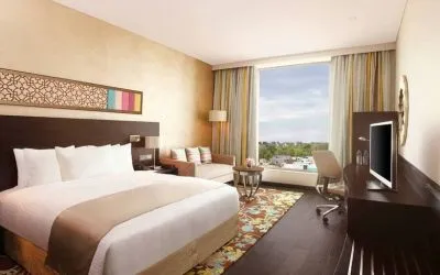 Spacious executive day room with floor-to-ceiling window, large desk, television, king bed at the Hilton Jaipur.