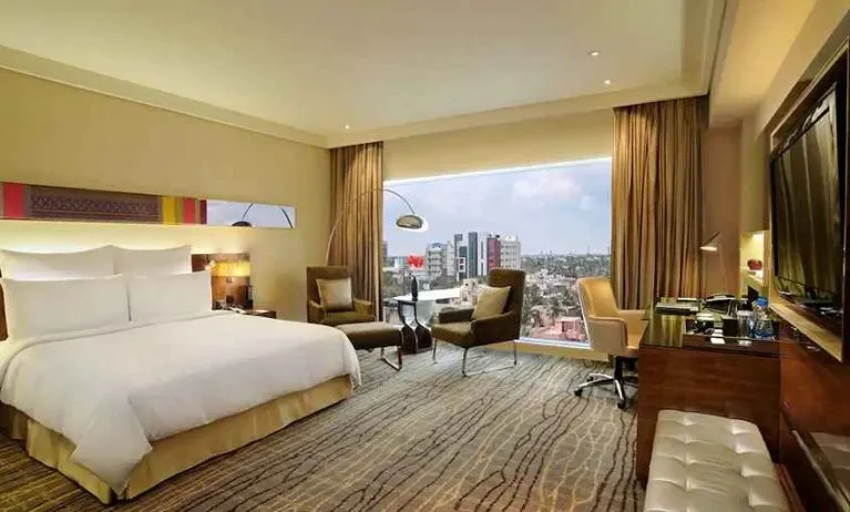 comfortable delux king room with TV, business desk, and lounge area at Hilton Chennai.