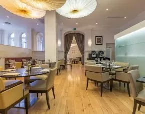 Tables and chairs in the airy, well-lit hotel restaurant.
