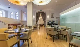 Tables and chairs in the airy, well-lit hotel restaurant.