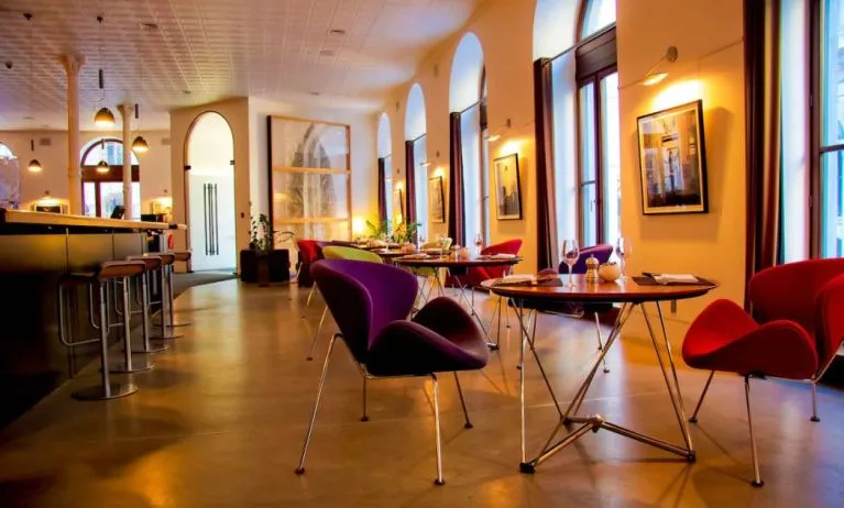 The hotel restaurant has a bar and small tables for diners to enjoy a refined breakfast experience.