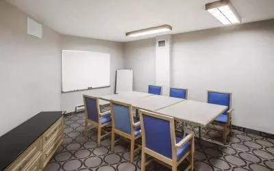Hotel meeting room with space for half a dozen attendees around a table, and a whiteboard nearby.