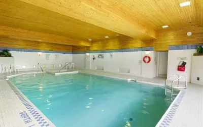 The hotel’s indoor pool is brightly lit and has chairs by the side.