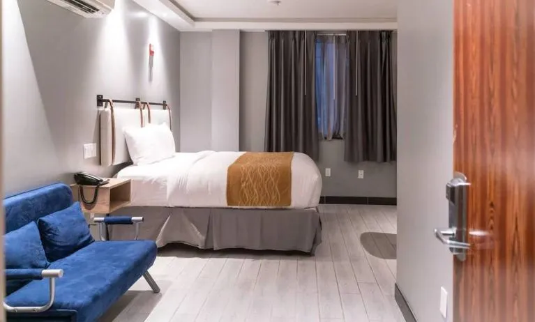 Double bedroom in the Madison LES Hotel, with window, telephone, and seating.