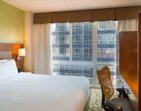 A Hilton Garden Inn Midtown East guest room with king-sized bed and floor-to-ceiling windows.