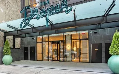 The hotel’s exterior, with The Draper, Ascend Hotel Collection’s name, awning, and large potted plants.