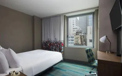 A single bed guest room in the Aloft Manhattan Downtown - Financial District, with TV and workspace desk and chair.