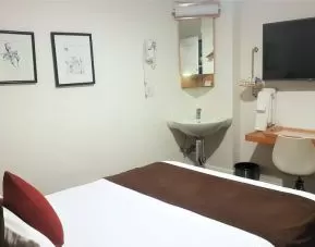 Guest room inside The Mosser Hotel, featuring a workspace desk and chair plus large TV.