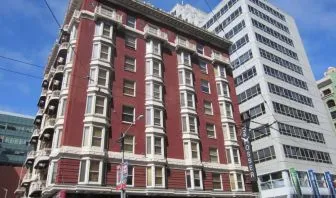 Exterior of the Mosser Hotel, with vertical sign and vibrant red brick hue.