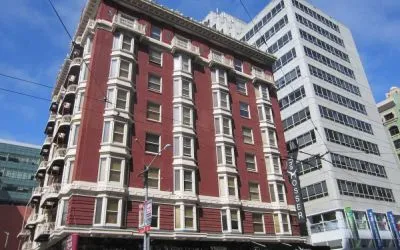 Exterior of the Mosser Hotel, with vertical sign and vibrant red brick hue.
