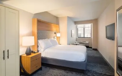 Guest room in the Holiday Inn Express Wall Street, with large television, chairs, and window.