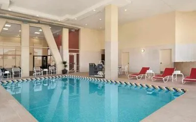 Lovely indoor pool with surrounding seating area and sun beds at Homewood Suites by Hilton University City.