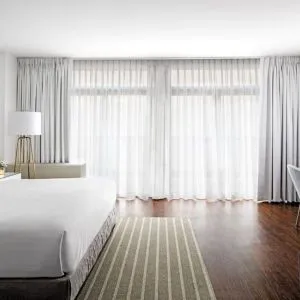 King bedroom with desk, chair, and natural light at St Gregory Hotel.
