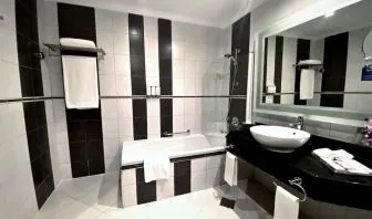 Guest bathroom with shower and bath at Millennium Central Doha.