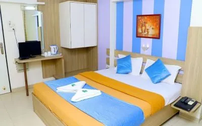 King bed in brightly lit room at Hotel Alka Residency.