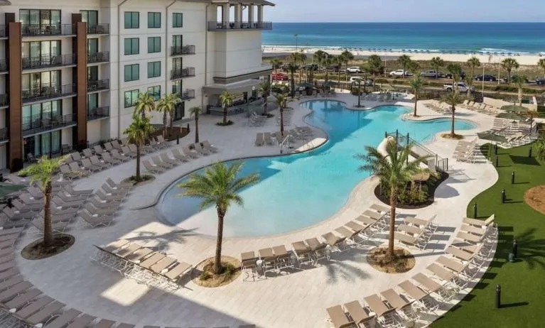 Beautiful outdoor pool with lounge chairs at Embassy Suites By Hilton Panama City Beach Resort.