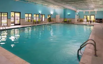 Sonesta Select Nashville Airport Suites’ indoor pool is brightly lit, has chairs by the side, and is adjacent to the patio.