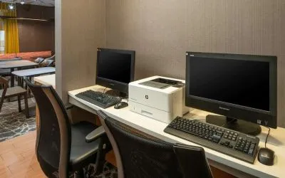 The hotel business center includes a pair of computer workstations and a printer.