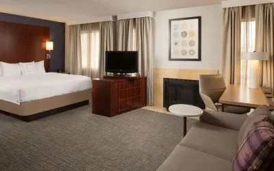 Sonesta ES Suites Nashville Brentwood king bed guest room, furnished with sofa, desk, and TV.