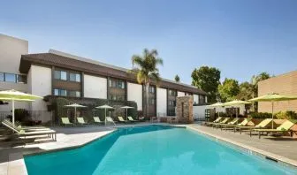 The outdoor pool of Sonesta Silicon Valley has nearby sun loungers, tables and chairs, and plenty of shade available.