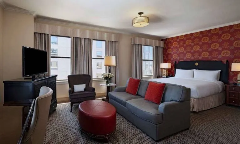 Double bed guest room in The Stephen F Austin Royal Sonesta Hotel, furnished with sofa, chair, desk, and television.