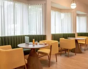 The hotel’s breakfast area has comfy seating, stylish tables, and large windows.