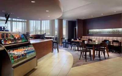 Sonesta Select Atlanta Cumberland Galleria’s dining area features a bar, both tall stool and table seating, and large windows.