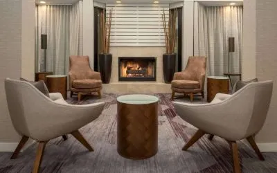 Sonesta Select Seattle Bellevue Redmond’s lobby includes coffee tables and comfy chairs close to a fireplace.