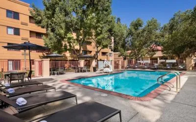 The outdoor pool at Sonesta Select San Jose Airport features a lift, and has nearby sun loungers and shaded tables and chairs.