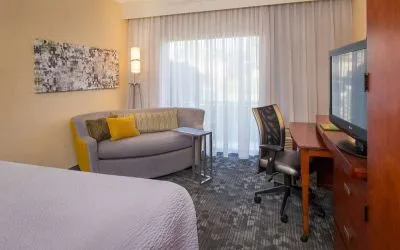 Double bed guest room in Sonesta Select Charlotte University Research Park, furnished with TV, chair, and sofa.