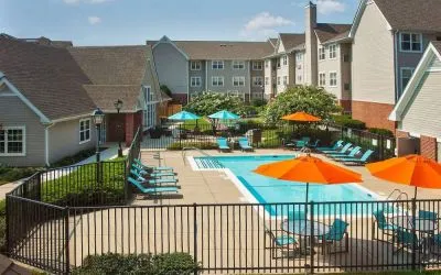 Sonesta ES Suites Baltimore BWI Airport’s outdoor pool is ringed by a fence, within which there are sun loungers, plus shaded tables and chairs.