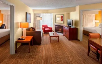 Double bed guest room in Sonesta ES Suites Allentown Bethlehem Airport, including lounge with sofa, TV, armchair, and fireplace.