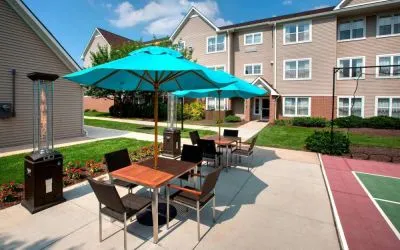 Sonesta ES Suites Allentown Bethlehem Airport’s patio is furnished with shaded tables and chairs.