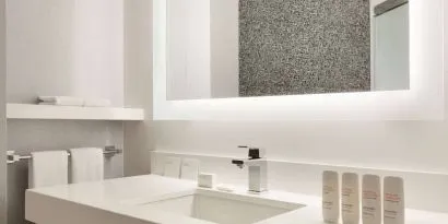 Guest bathroom in the hotel, including a range of toiletries, towels, and a sink.