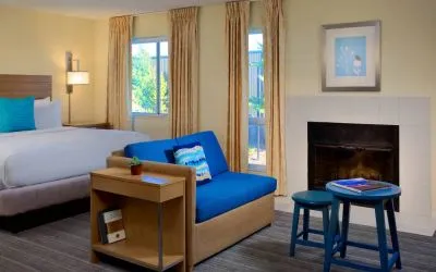 Sonesta ES Suites Flagstaff double bed guest room, featuring sofa, stool, coffee table, and fireplace.