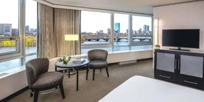 Royal Sonesta Boston double bed guest room, featuring wonderful city views, a widescreen TV, two chairs, and a coffee table.