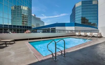 Sonesta Los Angeles Airport LAX’s outdoor pool has loungers by the side and towering buildings nearby.