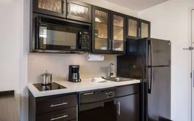 Sonesta Simply Suites Dallas Galleria guest room kitchen, furnished with fridge-freezer, hob, oven, and microwave.