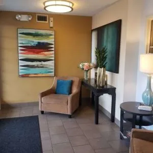 The hotel lobby has an armchair, potted plants, and art on the walls.
