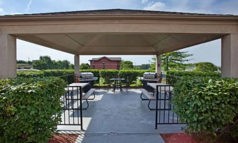 Sonesta Simply Suites Pittsburgh Airport’s gazebo features seating and tables outdoors and under cover, with two barbecues and a surrounding hedge.