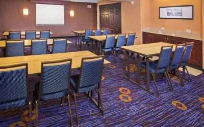 Meeting room in Sonesta Select Tinton Falls Eatontown, with tables arranged in a classroom format facing a projector screen.