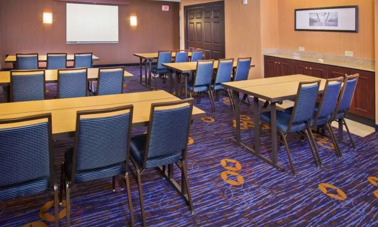 Meeting room in Sonesta Select Tinton Falls Eatontown, with tables arranged in a classroom format facing a projector screen.