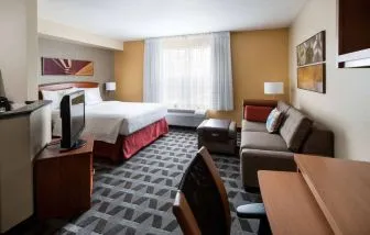 Sonesta Simply Suites Seattle Renton double bed guest room lounge, including sofa, TV, chair, and window.