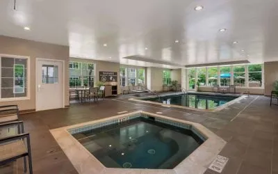 Sonesta ES Suites Parsippany Morris Plains’ indoor pool has a hot tub nearby, chairs and sun loungers nearby, and large windows.