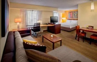 Double bed guest room in Sonesta ES Suites Birmingham Homewood, furnished with TV and sofa, plus workspace desk and chair.