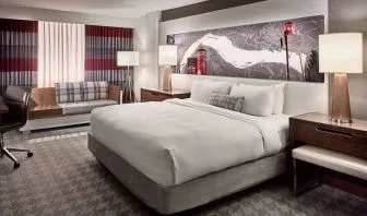 Double bed guest room in Sonesta Philadelphia Rittenhouse Square, including art on the wall, bedside lamps, chair, and a sofa.